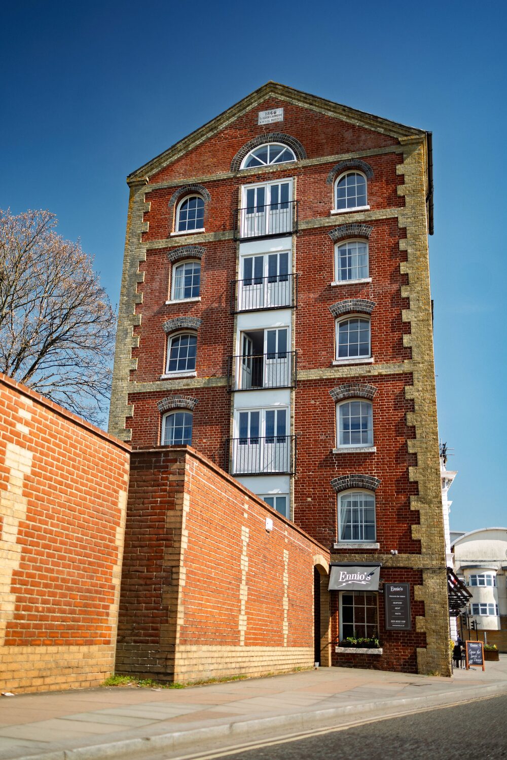 The full six-storey Victorian warehouse of Ennios on the old waterfront of Southampton, against a blue sky